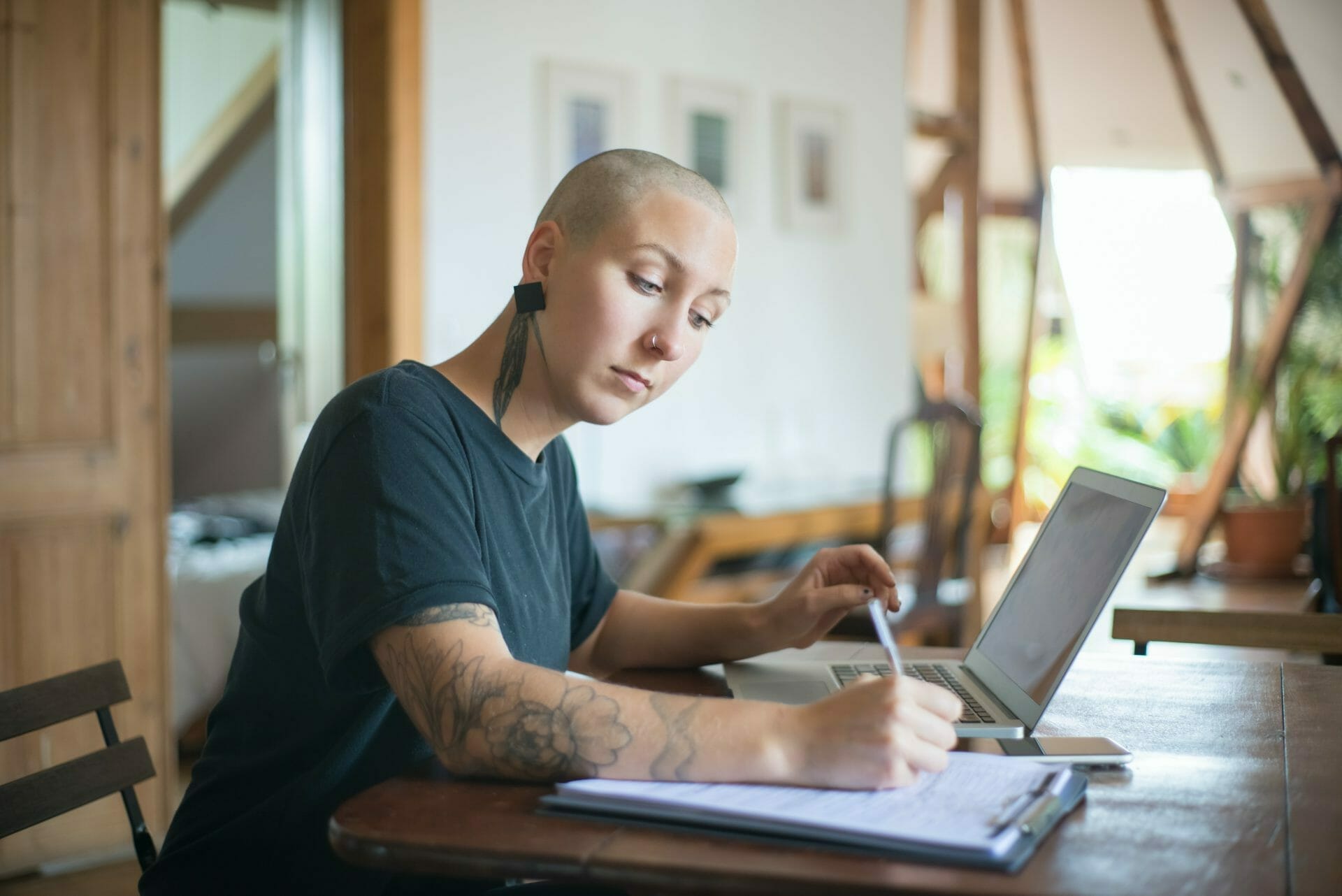 Young cancer patient working on a laptop and writing notes, representing financial assistance for multiple myeloma patients.