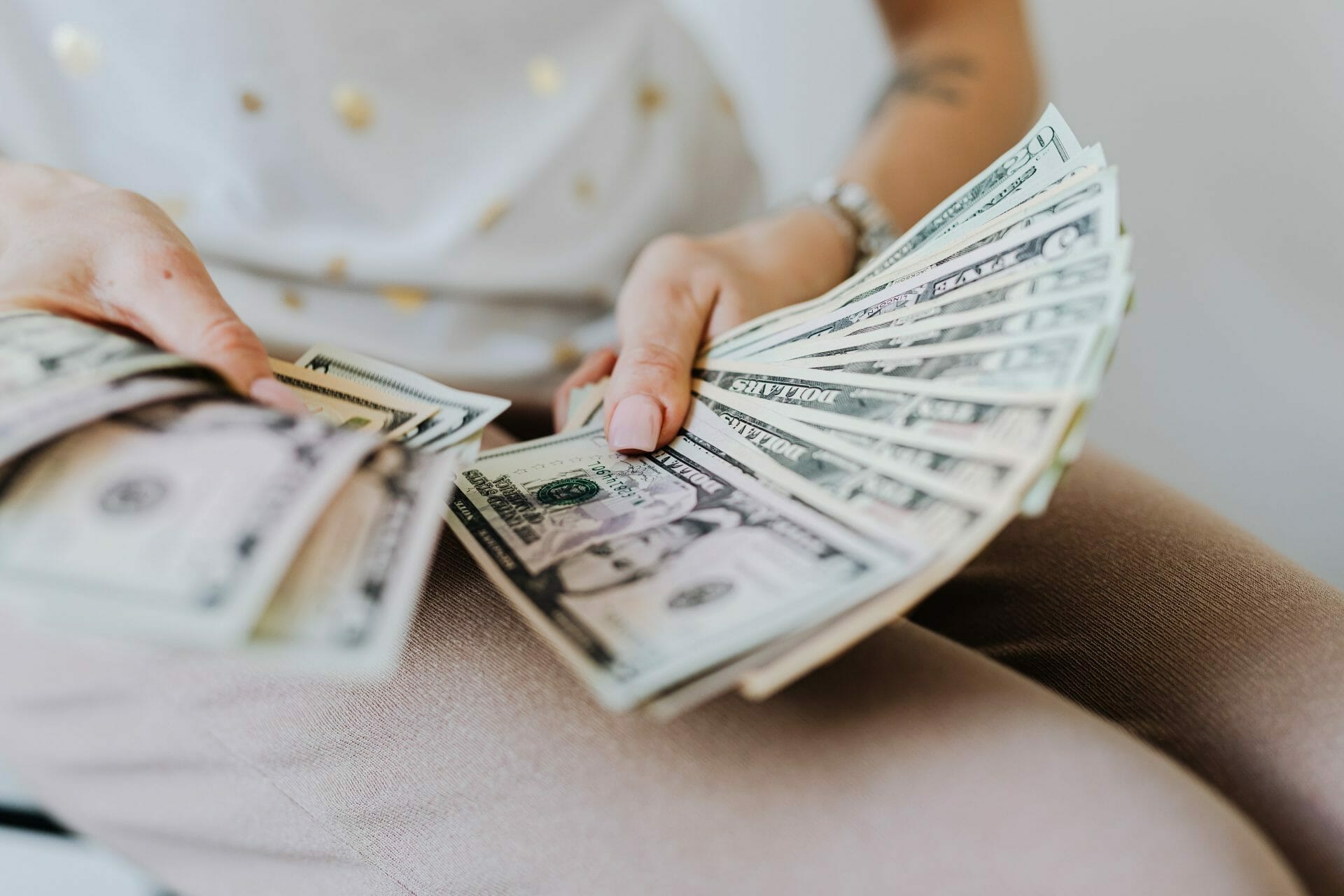 Person counting dollar bills, symbolizing financial assistance for multiple myeloma patients.