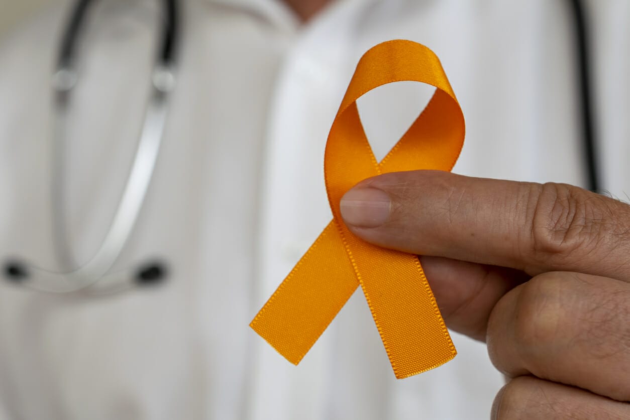 Doctor holding an orange ribbon symbolizing awareness and financial support for renal cancer patients.